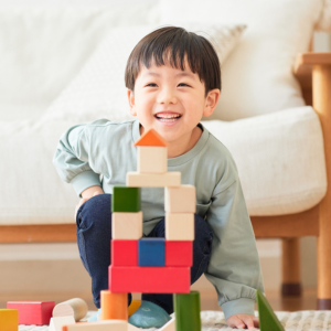 Little boy smiling and kneeling on floor, playing with blocks