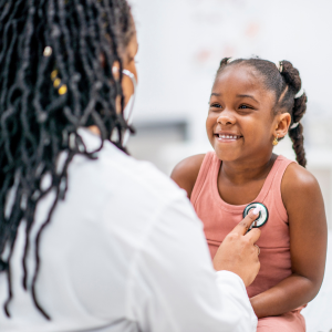 Little girl smiling, being examined by doctor