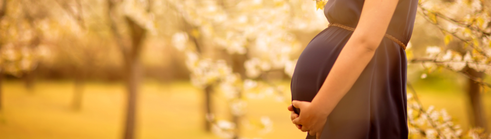 Pregnant woman outside, holding belly