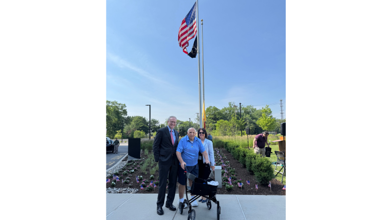 employees posing for photo in front of the american flag