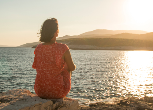 A woman looking out over a sunset on the water