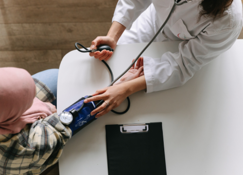 woman getting her blood pressure taken by a doctor