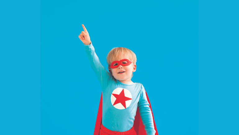 Young boy wearing a superhero costume, with his hand in the air