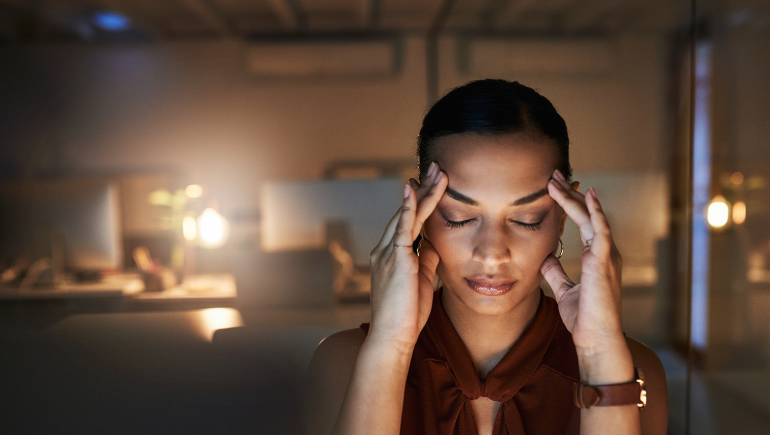 A woman with her eyes closed, fingers on her forehead, trying to stay calm