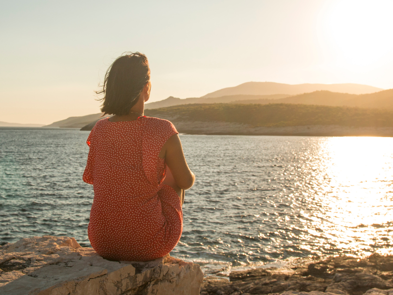 A woman looking out over a sunset on the water